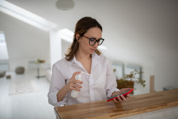 Young woman disinfecting smartphone at home