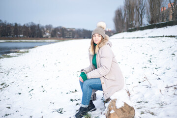 a girl in winter sits on a deck, a woman on the background of the river in winter, a person admires nature in winter, a woman's portrait on the background of the embankment, loneliness, happiness