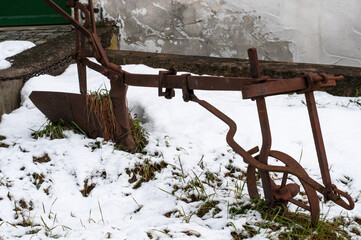 a rusty old plough in a snowy frontyard