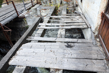 Old broken wooden bridge with gaps over a fast river
