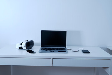 Work table on which there is a laptop, virtual reality glasses a