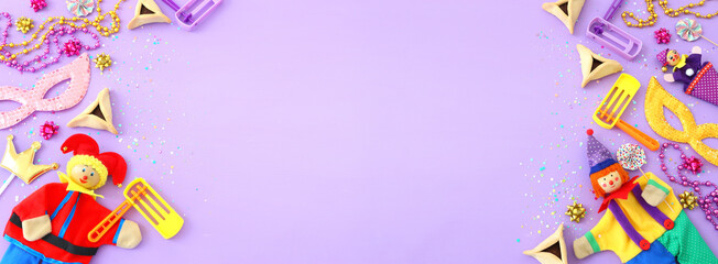 Purim celebration concept (jewish carnival holiday) over wooden purple background. Top view, flat lay