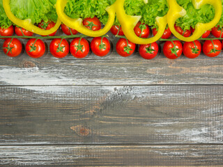 Fresh cherry tomatoes, lettuce, sweet peppers on a wooden background.