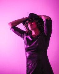 Studio lifestyle, a pretty young Caucasian woman in a session with elegant clothes and sunglasses, with neon pink light