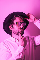 Studio lifestyle, a young Caucasian man with a seductive look wearing sunglasses, with neon pink light in a vertical photo