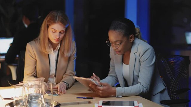 Attractive Multi-Race Corporate Female Couple Chatting in Conference Room Working Long Hours Creating New Project for Company Together. Workaholics.