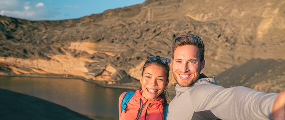 Travel interracial couple tourists traveling in Spain taking selfie photo on hike. Banner panoramic...