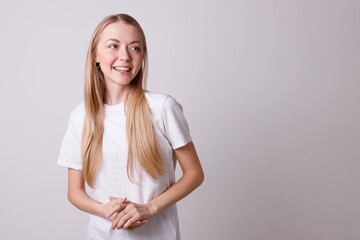 Beautiful smiling girl in a white T-shirt on a white background looks to the side