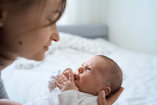 Young beautiful mother holds a baby. Mom kisses her baby. Children's bedroom. Cozy. High quality photo
