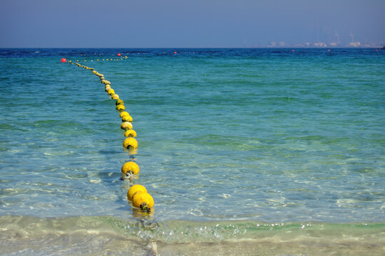 Seascape with floating buoys and rope dividing area on beach. Blue water on sea shore of Al Mamzar Beach Dubai