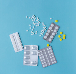 White and yellow pills flat lay for blogger medicine content with copy space on blue background