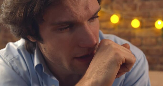 Close up of young depressed man sitting at home and crying