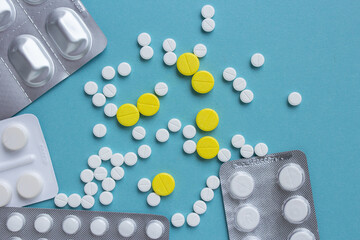 White and yellow pills flat lay for blogger medicine content with copy space on blue background