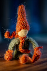 Handmade crochet autumn Gnome, with red hat and scarf, sitting position.