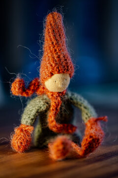 Handmade crochet autumn Gnome, with red hat and scarf, sitting position.