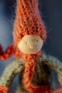 Handmade crochet autumn Gnome, with red hat and scarf, zoomed in on the face.