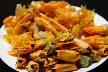 Red heads of boiled shrimp on a plate after eating.