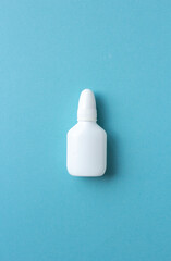 Bottle of white nasal spray isolated on blue background, copy space
