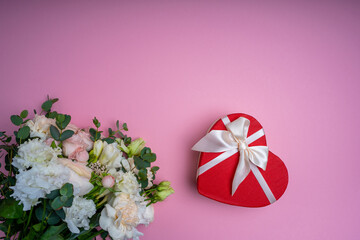 A close up of a flower and a heart gift box pink background Bouquet of flowers Valentin's day gift Top view with copy space for a text Greeting card background.Selective focus High quality