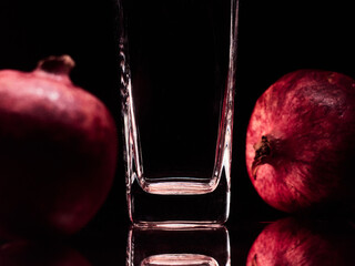 Glass in the low-key lighting and surface reflection with two pomegranates