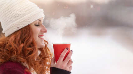 Close up. Woman in hat holding red craft glass of hot coffee. Girl warming up and happy smiling. Christmas Holidays. Copy space. Mockup for design. People and warming drink concept. Steaming beverage