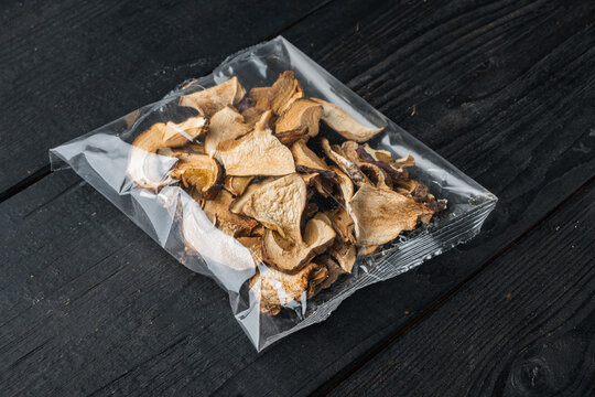 Dried mushrooms, on black wooden table background, in plastic pack