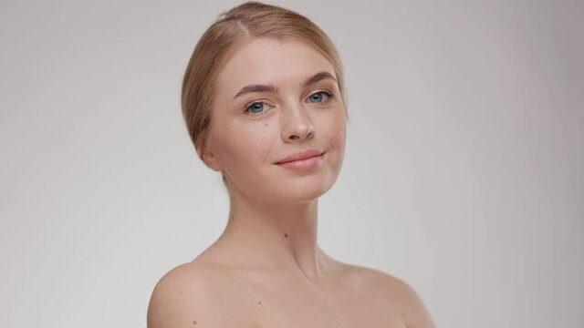 Beauty portrait of an attractive smiling sensual young woman. Close up. Adorable young half-naked woman look at the camera and smiling. Advertising fresh clean healthy skin care concept.