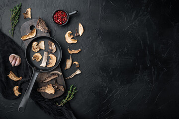 Dried porcini mushrooms in cast iron frying pan, on black background, top view flat lay , with space for text  copyspace