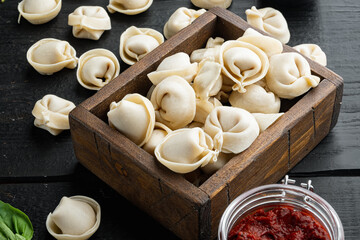 Italian tortellini with fresh ricotta leaves and tomatoes, on black wooden table background