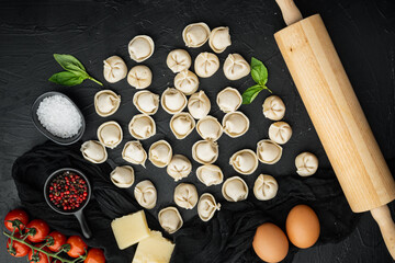 Obraz na płótnie Canvas Tasty raw tortellini with flour and basil, on black background , top view flat lay