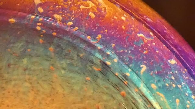 Swirling colorful soap bubble close up on black background