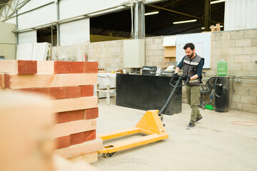 Male worker is about to load a pallet jack with wood