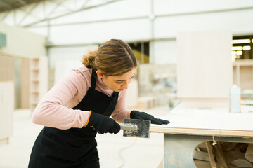 Side view of a beautiful woman working on carving a table