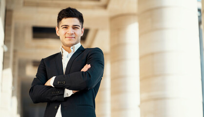 Fototapeta premium a man in a black business suit and white shirt looks at the camera. works in a bank in the city center. Dark-haired appearance. Sunny Light is a confident director of the finance department.