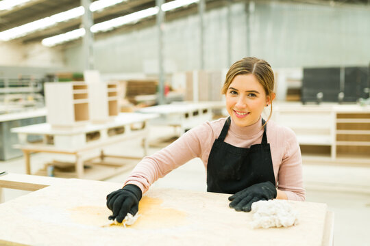 Beautiful Woman Staining A Wood Cabinet With A Sponge