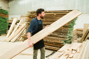 Hispanic worker holding a wooden board in a woodshop