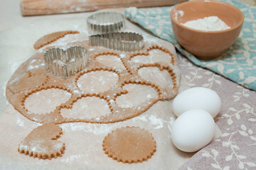Cutting out heart-shaped cookies from raw dough using cookie cutters.