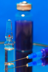 Medical ampoules and syringe for injection lie on the surface of the mirror, reflecting in it. Vaccination for protection against coronavirus. Health care during a pandemic