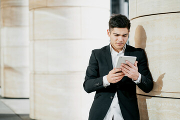banker business man employee working in a business center in a bank. holds a tablet and writes a message. the man is dark-haired of European appearance. business suit and white shirt