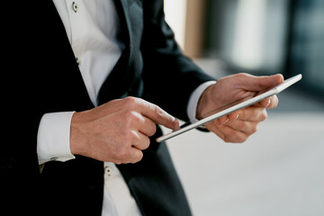 holding a tablet computer in the hands of a business man stylish business suit. hairstyle of the barbershop. copy space