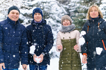 family portrait in the winter forest, parent and children, they throw snow, beautiful nature with bright snowy fir trees