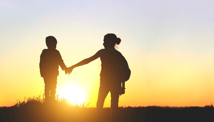 Friendly family, children, travel, family value concept. Elder sister and her younger brother looking on sunset. Children walking at sunset.