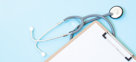 A wooden clipboard and stethoscope with white paper on it, set against a blue background