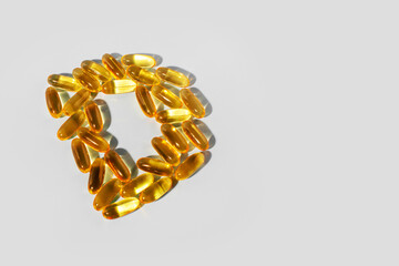 Yellow gelatin capsules on a gray background in the shape of the letter D. Food supplement, vitamin D.