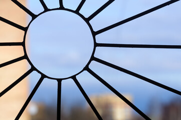 View through the lattice on the window in the shape of the sun on the blue sky and blurred houses. Freedom and life concept