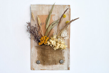 Still life with wild dry grass, yellow and violet wildflowers on rustic background, isolated