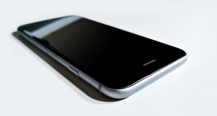 Black-gray mobile phone laying down on a white surface