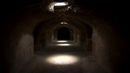 Fototapeta na wymiar Passage through a dark roman basement. Basement under the Amphitheater in El Jem, Tunis. Ancient roman building. The camera moves away