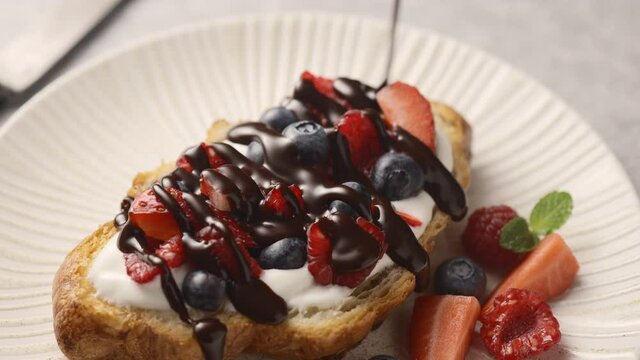 Croissant with berries and yogurt poured with chocolate sauce, delicious breakfast. Close-up 