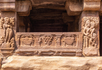 Aihole, Karnataka, India - November 7, 2013: Chalukya Shiva Temple. Closeup of statues and frescos at entrance in brown stone showing couple in love, and other woman.